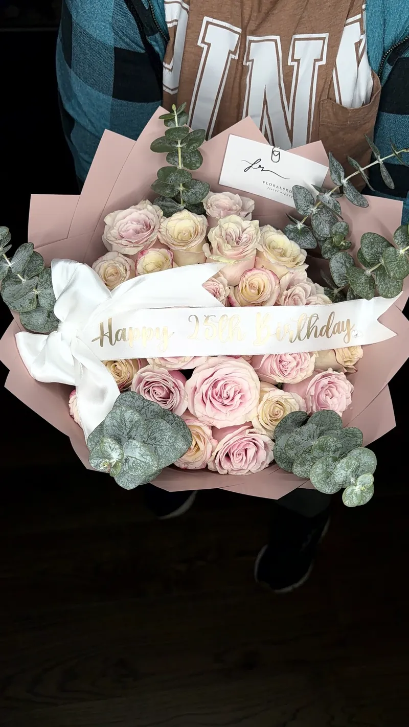 Blush and cream roses with eucalyptus in a dusty-pink wrap, finished with a Happy 25th Birthday sash.