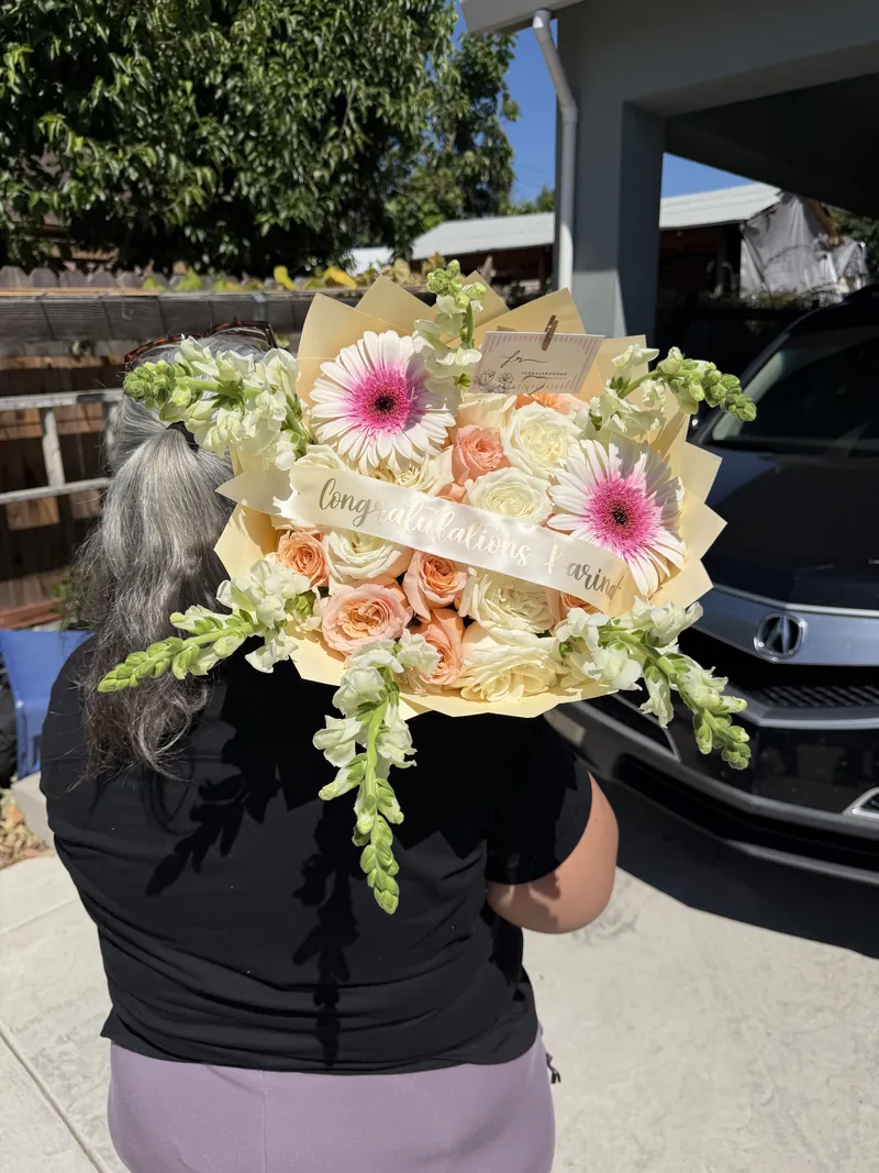 Pink gerbera daisies, peach roses and snapdragons in a cream wrap with a Congratulations sash.