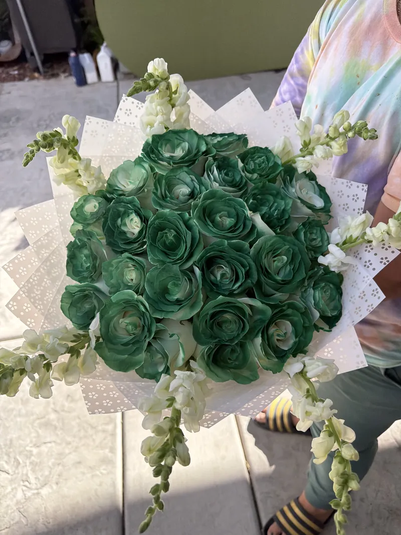 Emerald-tinted roses with white snapdragons in an eyelet-lace wrap.