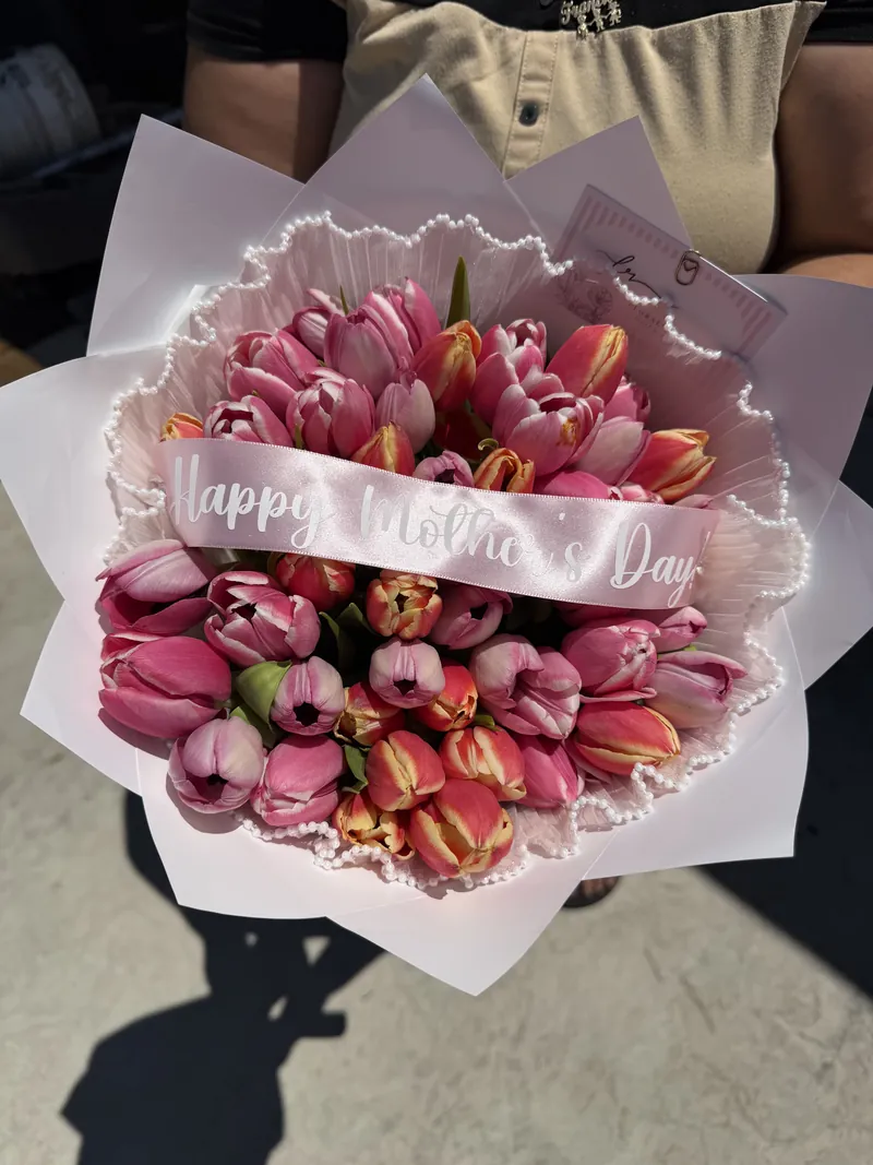 Pink and flame-tipped tulips in a pearl-edged white wrap with a Happy Mother's Day sash.