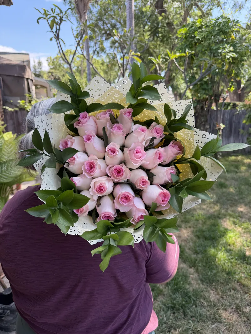 Pink roses framed with glossy greenery in an eyelet-lace wrap.
