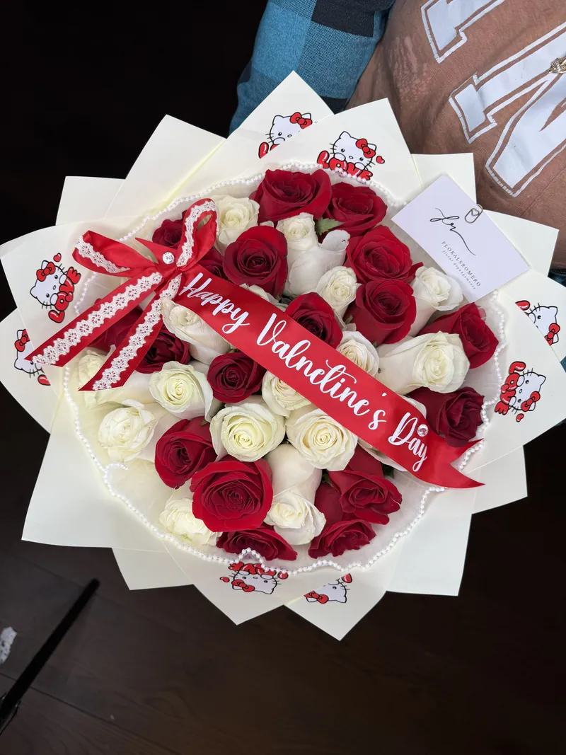 Red and white roses in a printed wrap with a pearl edge and a red Happy Valentine's Day sash.